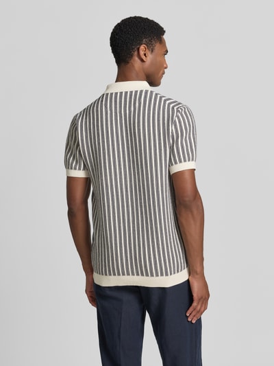 Męski model nosi Regular Fit Poloshirt in Strick-Optik od MCNEAL, czarno-białe paski, kołnierzyk polo, bawełna, krótki rękaw, imitacja dzianiny, długość tyłu w rozmiarze M: 71 cm, długość rękawów: 24 cm, widok całej sylwetki z tyłu.