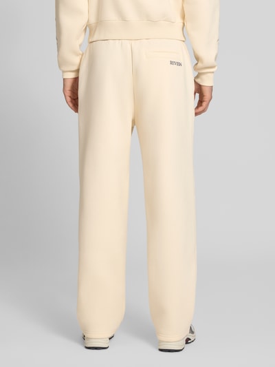 Männermodel trägt Straight Fit Sweatpants mit floraler Stickerei von REVIEW in Beige, Baumwoll-Mix, elastischer Bund, Ganzkörperansicht Rückansicht.