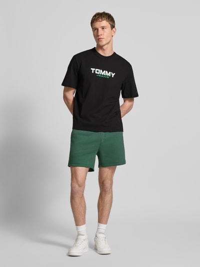 Männermodel trägt Regular Fit T-Shirt aus reiner Baumwolle von Tommy Jeans, Optik: Unifarben, Label-Schriftzug, Ganzkörperansicht von vorne.