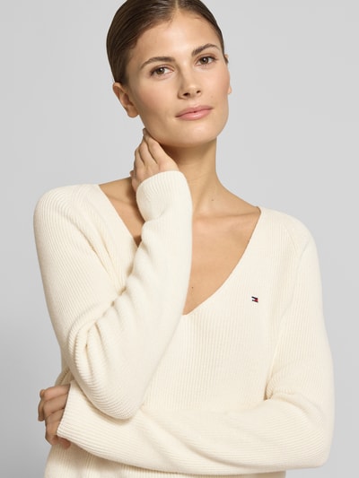 Vrouwenmodel draagt Regular Fit Gebreide pullover uit puur katoen van Tommy Hilfiger, gestreepte look, V-hals, lange raglanmouwen, ribtricot, logostitching, kleur effen, Nahaufnahme bovenlichaam.