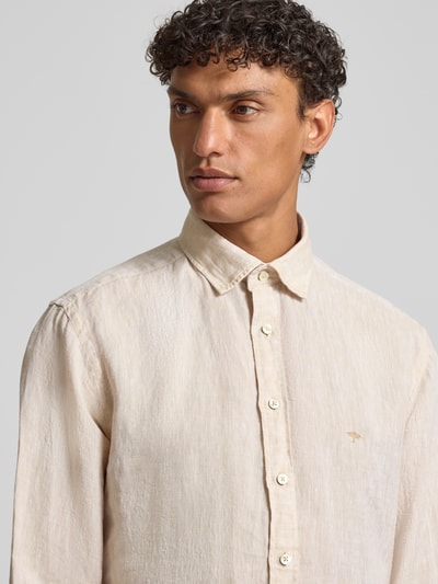 Męski model nosi Slim Fit Leinenhemd mit Haifischkragen od Fynch-Hatton, jasny beż, czysta len, krój slim fit, detal z logo, długość tyłu w rozmiarze M: 77 cm, szerokość w rozmiarze M: 47 cm, długość rękawa w rozmiarze M: 61 cm, faktura lnu, widok na górną część ciała z przodu