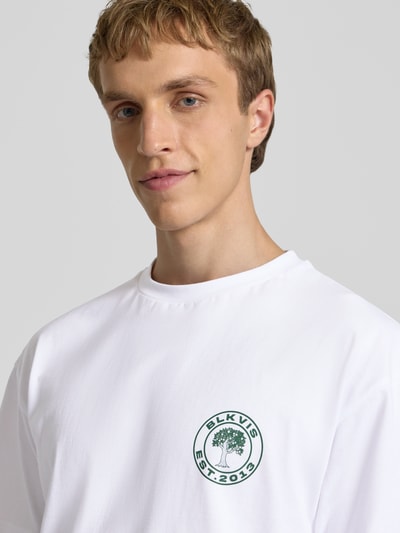 Mannenmodel draagt T-Shirt met Logo en Rundhalsausschnitt van BLKVIS in wit, pure katoen, regular fit, borstlogo, close-up bovenlichaam.