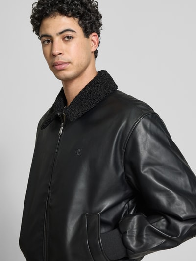 Männermodel trägt Regular Fit Jacke in Leder-Optik mit Umlegekragen von Calvin Klein Jeans, Schwarz, Zweiwege-Reißverschluss, Nahaufnahme Oberkörper.