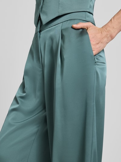 Kobieta nosi Hose mit weitem Bein und Falten von Jake*s Cocktail, satynowa tkanina, szerokie nogawki, fałdy, kieszeń z tyłu, szerokość w rozmiarze 36: 34 cm, długość nogawki od wewnątrz w rozmiarze 36: 82 cm, zbliżenie na górną część ciała