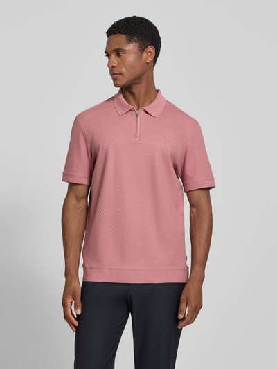 Männermodel trägt Regular Fit Poloshirt mit Strukturmuster Modell 'Tibaris' von JOOP! COLLECTION in Rosa mit Label-Stitching, Polokragen, Reißverschluss, Rückenlänge 70 cm bei Größe M, Ganzkörperansicht von vorne.