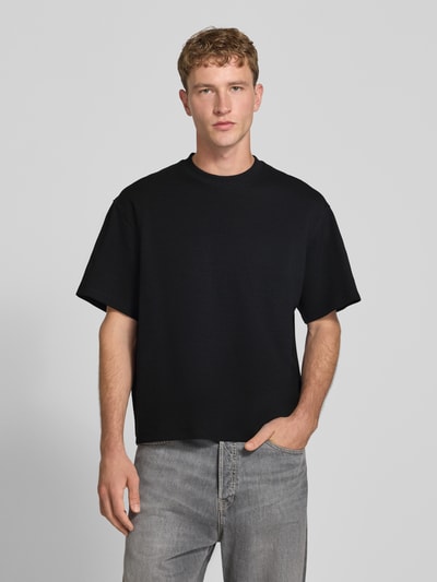 Männermodel trägt Relaxed Fit T-Shirt aus elastischem Baumwoll-Mix Modell 'SCUBA' von JACK & JONES in Schwarz, Ganzkörperansicht von vorne. Rückenlänge bei Größe M: 68 cm, Rundhalsausschnitt.