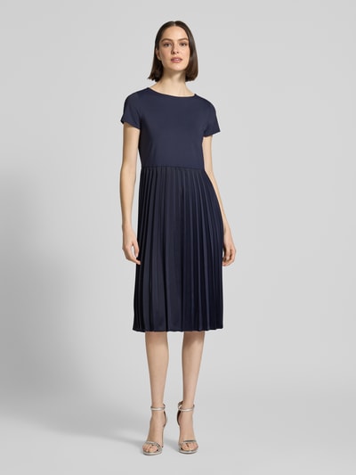 Frauenmodel trägt Midikleid in Plissee-Optik von Christian Berg Woman Selection in Dunkelblau, Elastischer-Material-Mix, Tailliert, Rundhalsausschnitt, Kurzärmelig, feine Faltenstruktur, Rückenlänge 108 cm, Brustweite 42 cm, Ärmellänge 15 cm, Ganzkörperansicht von vorne.