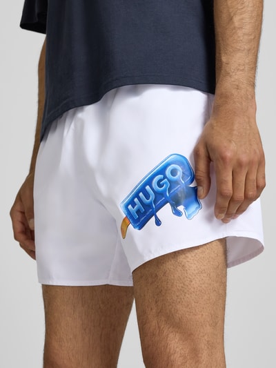 Männermodel trägt Badeshorts mit Motiv-Print von Hugo Blue in Optik: Unifarben aus Popeline mit Gesäßtasche, Nahaufnahme Oberschenkel.