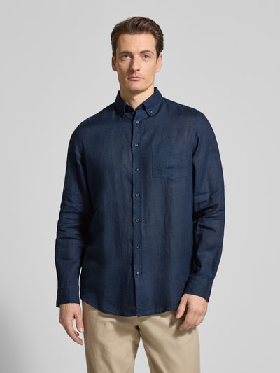 Męski model nosi Slim Fit Leinenhemd mit Brusttasche von Christian Berg Men, granatowy len, kołnierzyk typu button down, listwa guzikowa, brustasza, długość tyłu w rozmiarze M: 79 cm, szerokość ramion w rozmiarze M: 43 cm, długość rękawów w rozmiarze M: 68 cm, ganzkörperansicht von vorne.