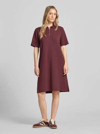 Frauenmodel trägt Polokleid mit kurzem Reißverschluss von Christian Berg Woman, Material-Mix mit Modal-Anteil, Gerader-Schnitt, Midikleid in Dunkelrot, strukturierte Oberfläche, Polokragen, Ganzkörperansicht von vorne.