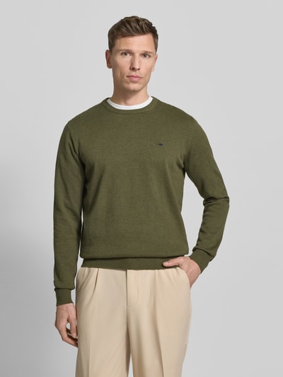 Männermodel trägt Strickpullover mit gerippten Abschlüssen von Fynch-Hatton in Oliv, reine Baumwolle, Regular-Fit, Rundhalsausschnitt, Label-Stitching, beige Hose, Ganzkörperansicht von vorne.