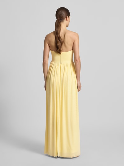 Frauenmodel trägt Cocktailkleid im Off-Shoulder-Look von Lipsy in Gelb, Maxikleid aus Material-Mix mit Stretch-Anteil, taillierter Schnitt, Rückenlänge 132 cm bei Größe 36, Brustweite 40 cm, Ganzkörperansicht Rückansicht.