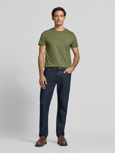Männermodel trägt Regular Fit T-Shirt aus reiner Baumwolle von Paul Smith in Olivgrün mit Label-Stitching, Ganzkörperansicht von vorne.