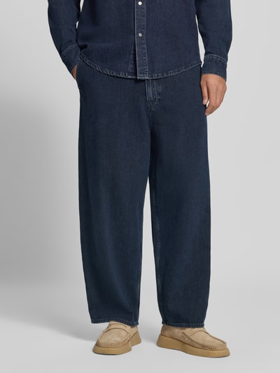 Männermodel trägt dunkelblaue Baggy Jeans aus reiner Baumwolle Modell 'Kaavo' von ARMEDANGELS, locker geschnitten, Ganzkörperansicht von vorne, Herren Baggy Jeans von ARMEDANGELS.