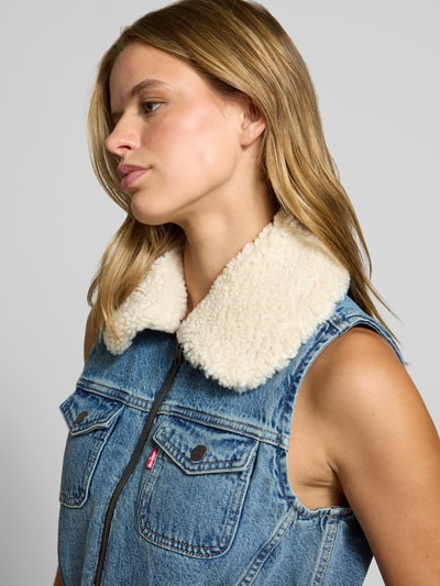 Frauenmodel trägt Regular Fit Weste aus reiner Baumwolle Modell 'TINY SHERPA VEST' von Levi's®, blaue Denim-Optik mit cremefarbenem Teddykragen, Nahaufnahme Oberkörper, Damen Weste von Levi's®.