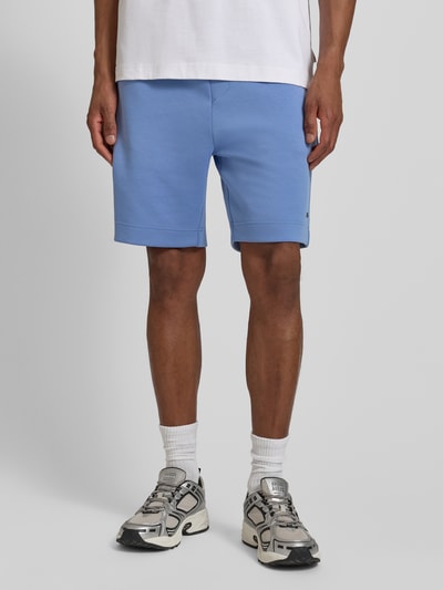 Männermodel trägt Regular Fit Sweatshorts aus Baumwoll-Mix Modell 'JT_GLOBE' von BOSS Green, efekt: jednolity kolor, krój regular fit, z napisem z logo, detale: szwy, ściągacz: elastyczny, tunel, wpuszczane kieszenie, boczna kieszeń zapinana na zamek błyskawiczny, wykończenie materiału: dzianina dresowa, mieszanka bawełny; Ganzkörperansicht von vorne.