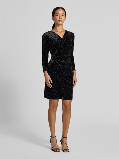 Vrouwenmodel draagt Samtkleid in Minilänge mit Stretch-Anteil van Apricot in zwart fluweel met all-over strassdetails, V-hals, wikkel-look, lange mouwen, getailleerde fit, korte lengte, ruches, Ganzkörperaanzicht van voren.