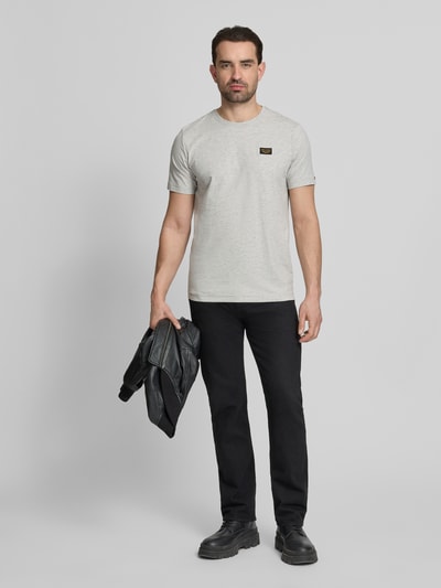 Męskimodel nosi T-Shirt mit Label-Details und Rundhalsausschnitt von PME Legend, mieszanka bawełny i elastanu, krój regular fit, długość tyłu w rozmiarze M: 70 cm, jasnoszary, czarne spodnie, gładka tekstura, całkowity widok z przodu