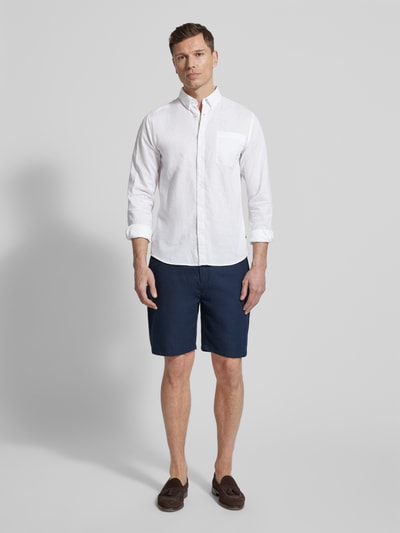 Męski model nosi Regular Fit Freizeithemd mit Leinen-Anteil von Matinique w białym kolorze, tkanina len-bawełna, krój regular fit, kołnierzyk button-down, listwa guzikowa, kieszeń na piersi, długość pleców w rozmiarze M: 64 cm, szerokość w rozmiarze M: 43 cm, długość rękawa w rozmiarze M: 68 cm, pełny widok z przodu.
