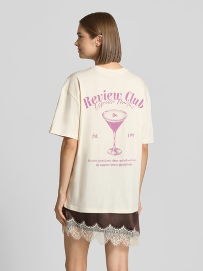 Frauenmodel trägt Oversized Fit T-Shirt aus reiner Baumwolle mit Label-Detail von REVIEW, Cremefarbe, Print auf der Rückseite, Ganzkörperansicht Rückansicht.