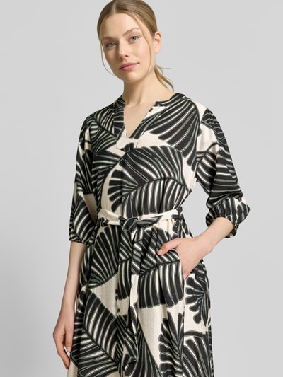 Frauenmodel trägt Knielanges Kleid aus Viskose-Mix mit Tunika-Ausschnitt von Christian Berg Woman Selection, floraler Allover-Print, Tailliert, Halbarm, Nahaufnahme Oberkörper.