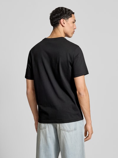 Männermodel trägt T-Shirt mit Logo und Rundhalsausschnitt von CHAMPION, schwarze Baumwolle, Regular Fit, Rückenansicht, Ganzkörperansicht Rückansicht.