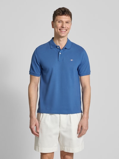 Männermodel trägt Slim Fit Poloshirt mit Logo-Stitching van Gant in blauw, puur katoen, polokraag, korte mouw, ruglengte 70 cm, Ganzkörperansicht van voren