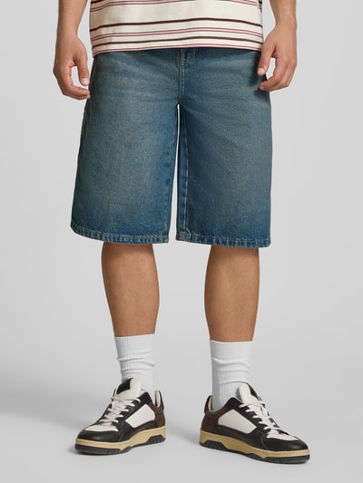Männermodel trägt Loose Fit Bermudas mit Eingrifftaschen van Dickies, blauwe denim, katoen, steekzakken, voorkant, geheel lichaam
