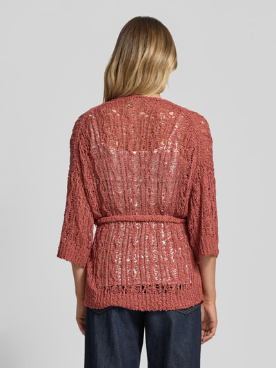 Vrouwenmodel draagt Strickjacke mit Bindegürtel und 3/4-Arm van Marc Cain in oudroze, luchtig gebreide bio-katoen, relaxed fit, open model, bindriem, driekwart mouw, ruglengte maat 36: 74 cm, mouwlengte 34 cm, volledig lichaamsbeeld achteraan.