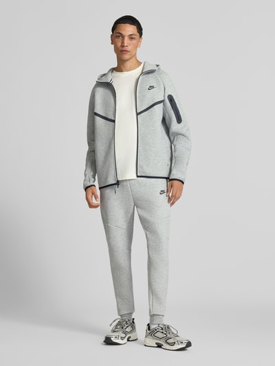 Männermodel trägt Slim Fit Sweathose aus Baumwoll-Mix von Nike in Hellgrau mit glatter Textur, Ganzkörperansicht von vorne. Herren Sweathose