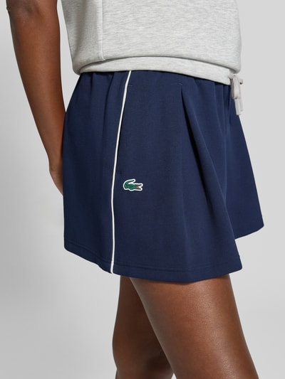Kobiece modelka nosi Relaxed Fit Shorts aus Baumwoll-Mix od Lacoste, damskie szorty sport, granatowy kolor, tekstura gładka, detal z boku, zbliżenie na biodra