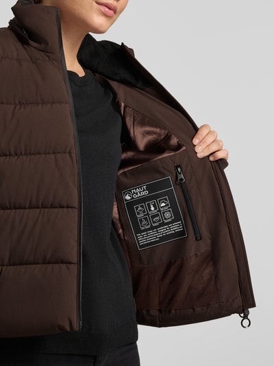 Frauenmodel trägt Jacke mit Daumenloch und Kapuze von NAUTGÅRD in Dunkelbraun mit seitlichen Reißverschlusstaschen, Nahaufnahme Oberkörper.