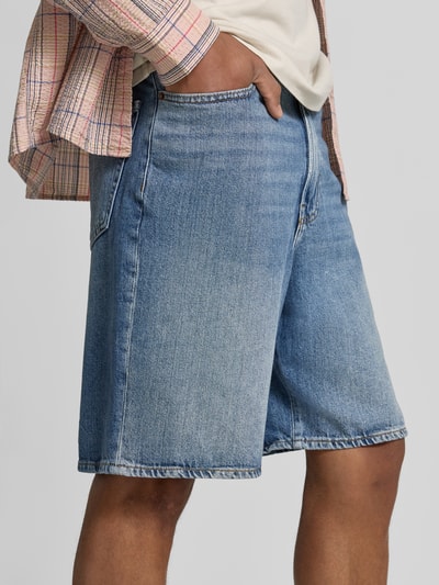 Männermodel trägt Bermudas im 5-Pocket-Design von GAP aus Baumwoll-Lyocell-Mix, Loose-Fit, mittleres Blau, Nahaufnahme Oberschenkel.