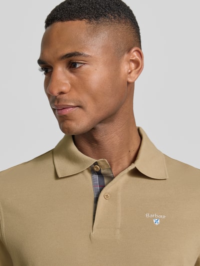 Männermodel trägt Regular Fit Poloshirt aus reiner Baumwolle von Barbour in Optik: Unifarben mit Label-Stitching-Applikation, Nahaufnahme Oberkörper.