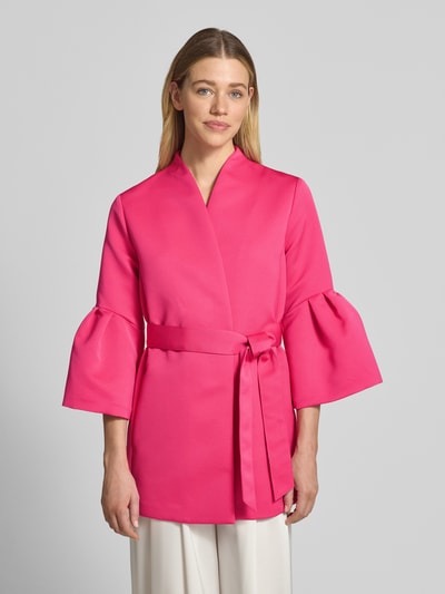 Frauenmodel trägt Blazer mit ausgestellten Ärmelabschlüssen von Marc Cain in Pink, Stehkragen, Stoffband, tailliert, Nahaufnahme Oberkörper.