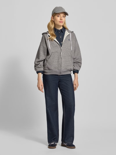 Modelka kobieca ma na sobie Sweatjacke mit Label-Stitching od Polo Ralph Lauren z bawełnianego miksu, krój relaxed fit, kaptur z troczkiem, zamek błyskawiczny, label-stitching, kieszeń kangurka, kolor szary, całościowy widok z przodu.
