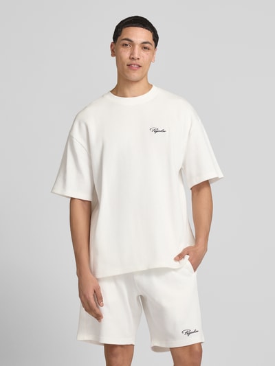 Männermodel trägt Oversized T-Shirt mit Strukturmuster von Pegador aus Baumwoll-Mix in Offwhite, Logo-Stitching, Ganzkörperansicht von vorne.