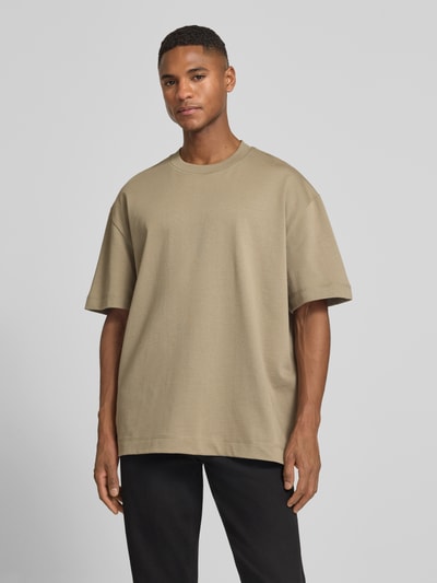 Męski model nosi T-Shirt mit Rundhalsausschnitt Modell 'Carl' od Les Deux, czysta bawełna, prosty krój, beżowy, całkowity przód, zdjęcie całopostaciowe z przodu.