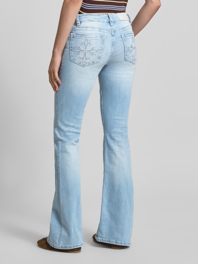 Frauenmodel trägt Flared Jeans im Used-Look Modell 'Poppy' von Gina Tricot in Hellblau, Baumwoll-Mix mit Stretch-Anteil, 5-Pocket-Design, Knopf-Reißverschluss, Bundweite bei Größe 36: 36 cm, Innenbeinlänge 86 cm, Ganzkörperansicht Rückansicht.