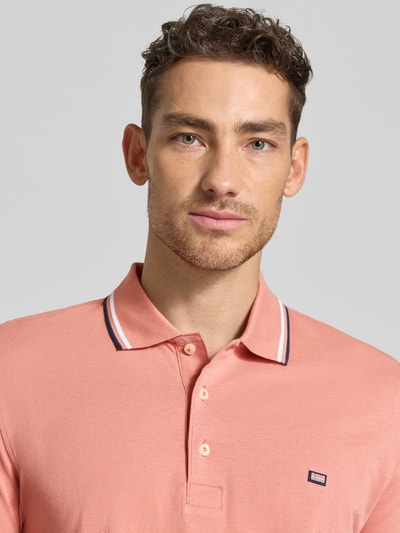 Männermodel trägt Regular Fit Poloshirt mit contraststrepen van Christian Berg Men van puur katoen in zalmroze, knoopsluiting, nahaufnahme oberkörper.