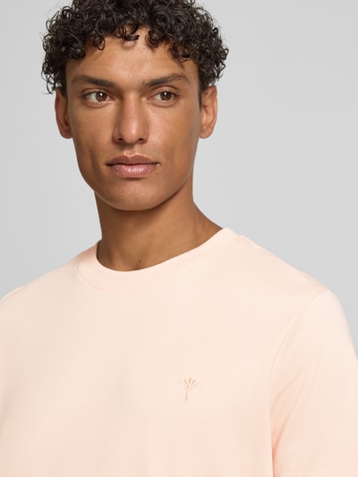 Männermodel trägt T-Shirt mit Logo-Stitching Modell 'Priamo' von JOOP! Collection in zartem Rosé, reine Baumwolle, Nahaufnahme Oberkörper.