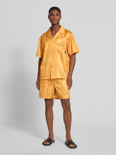 Męski model nosi Relaxed Fit Freizeithemd mit Reverskragen Modell 'Resort' von COLUCCI, elastyczna mieszanka materiałów, kolor żółty, krótki rękaw, brustasza, listwa guzikowa, naszywka z logo, długość tyłu w rozmiarze M: 70 cm, szerokość w rozmiarze M: 56 cm, długość rękawów w rozmiarze M: 26 cm, widok całej sylwetki z przodu.