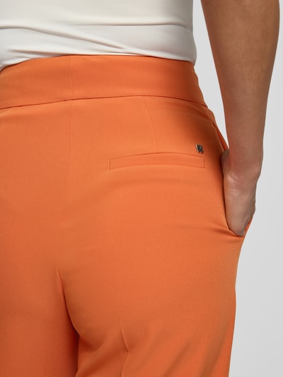 Frauenmodel trägt Wide Leg Weite Hose mit Gürtelschlaufen Modell 'HIMIA-1' von HUGO in Orange, glatte Textur, Nahaufnahme Rückansicht, Damen Weite Hose.