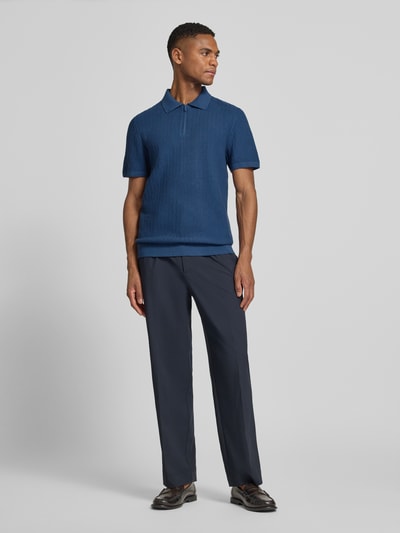 Männermodel trägt Poloshirt mit kurzem Reißverschluss und Polokragen von MCNEAL aus reiner Bio-Baumwolle in Blau, Body Fit, Ganzkörperansicht von vorne.