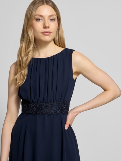 Frauenmodel trägt Knielanges Cocktailkleid mit Taillenband von Christian Berg Cocktail aus Chiffon in Dunkelblau, Taillierter Schnitt, Rundhalsausschnitt, Drapierungen, Damen Cocktail, Nahaufnahme Oberkörper. Rückenlänge bei Größe 36: 103 cm, Brustweite bei Größe 36: 36 cm.