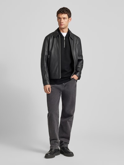 Męski model nosi Sweatshirt mit Polokragen und Reißverschluss od CK Calvin Klein, czarny materiał z fakturą, relaxed fit, widok z przodu.
