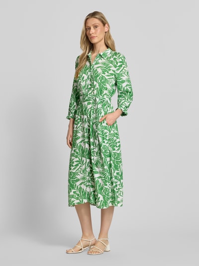 Modelka kobieca nosi Midikleid aus reiner Viskose mit Umlegekragen od More & More w zielony, kwiatowy wzór, pasek w talii, długie rękawy, krój slim fit, długość do połowy łydki, czysta wiskoza, szerokość w rozmiarze 36: 40 cm, długość tyłu: 125 cm, długość rękawa: 49 cm, ujęcie całej sylwetki z przodu.