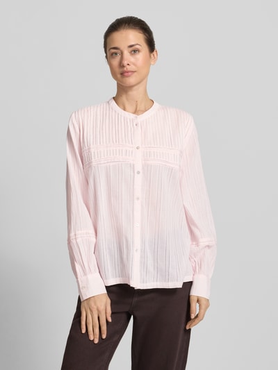 Modelka kobieca ma na sobie bluzkę z bawełny o kroju loose fit ze stójką, listwą guzikową, sportowymi mankietami i wzorem pointelle Bluse mit Mao-Kragen und Pointelle-Muster od Jake*s Casual, jasnoróżowy i brązowe spodnie, długość tyłu w rozmiarze 36: 62 cm, długość rękawów: 60 cm, zdjęcie całej sylwetki z przodu.