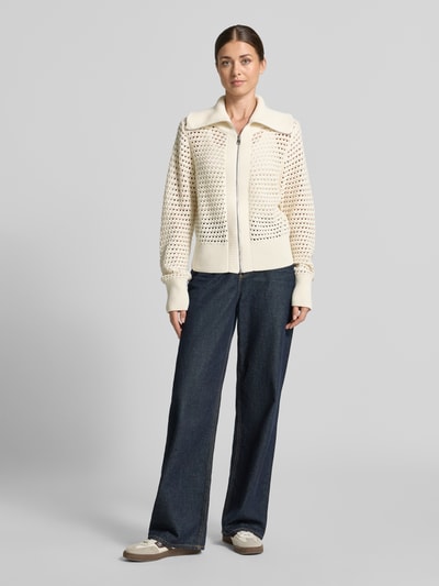 Frauenmodel trägt Regular Fit Cardigan aus reiner Baumwolle Modell 'Eloise' von VARLEY, cremefarbene Strick-Optik, Umlegekragen, Reißverschluss, Ganzkörperansicht von vorne.