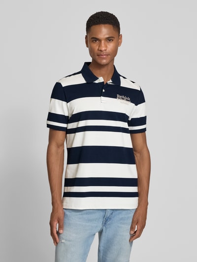 Männermodel trägt Regular Fit Poloshirt aus reiner Baumwolle von s.Oliver RED LABEL, gestreift in Dunkelblau und Weiß, Piqué-Struktur, Ganzkörperansicht von vorne.